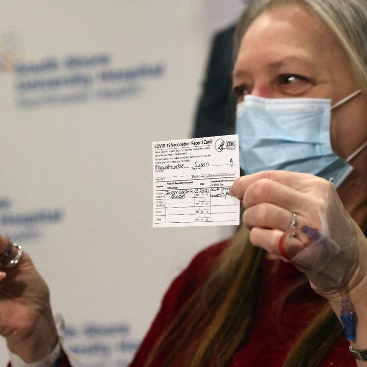Una mujer sostiene una tarjeta de vacunación contra el COVID-19