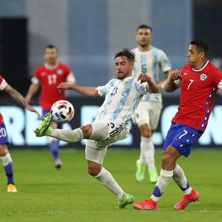El argentino Nicolás Tagliafico intenta controlar el balón ante la presencia del chileno Alexis Sánchez, en un partido por las eliminatorias sudamericanas a Qatar 2022.