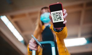 Una mujer sostiene su teléfono mientras muestra un código QR.