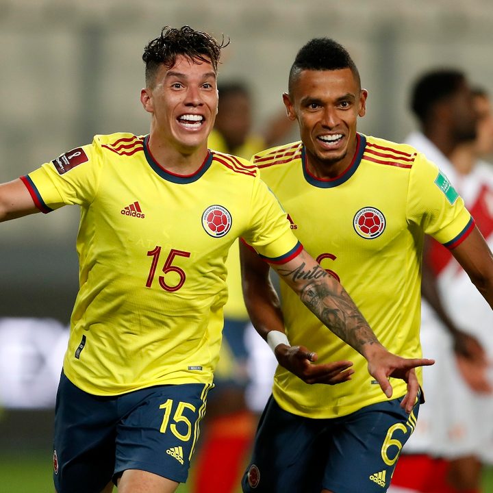 Mateus Uribe de la selección de fútbol de Colombia corre a través del campo para celebrar un gol, mientras es perseguido por su compañero de equipo William Tesillo.