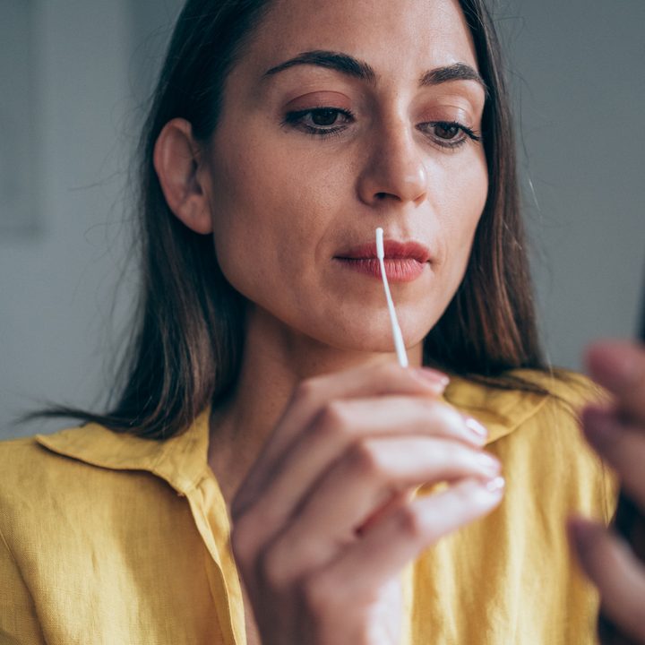 Mujer mira el celular mientras sostiene prueba casera de COVID
