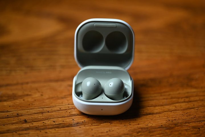 Unos Samsung Galaxy Buds 2 abiertos, sobre una superficie de madera.