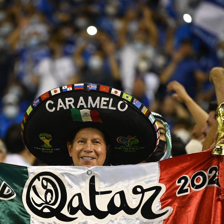 Un fanático de México con una bandera mexicana con la leyenda de Qatar 2022 y un gorro tradicional mexicano
