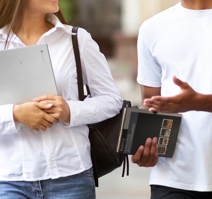 Dos personas en la calle; la mujer está sosteniendo una computadora portátil Samsung Chromebook Go.