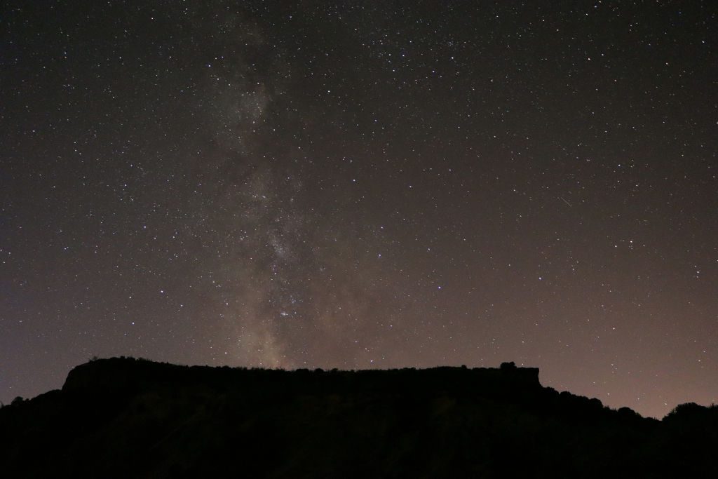 La imagen muestra una montaña y el cielo nocturno sobre un sector desértico.