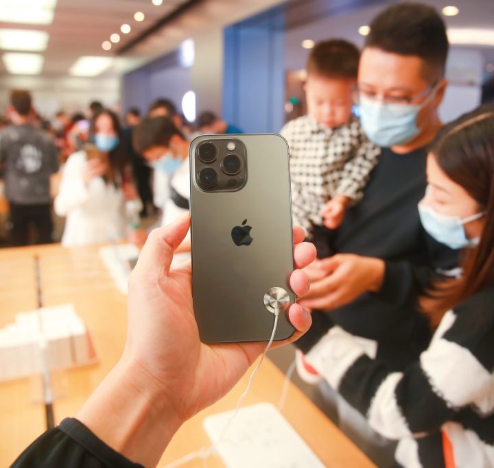Una persona sostiene un iPhone frente a un grupo de personas en una tienda en China.
