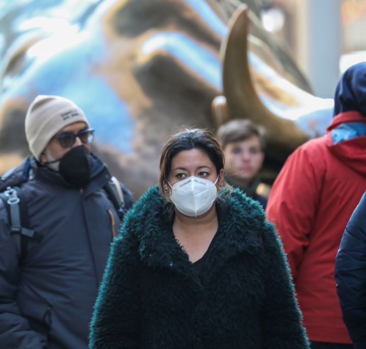 La imagen muestra a una mujer caminando usando una mascarilla.