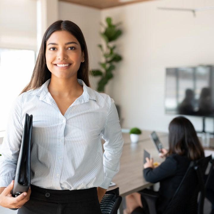 mujer profesionista en un espacio de trabajo con otras personas.