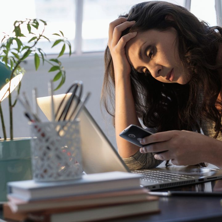 Mujer revisando su celular al interior de su casa.