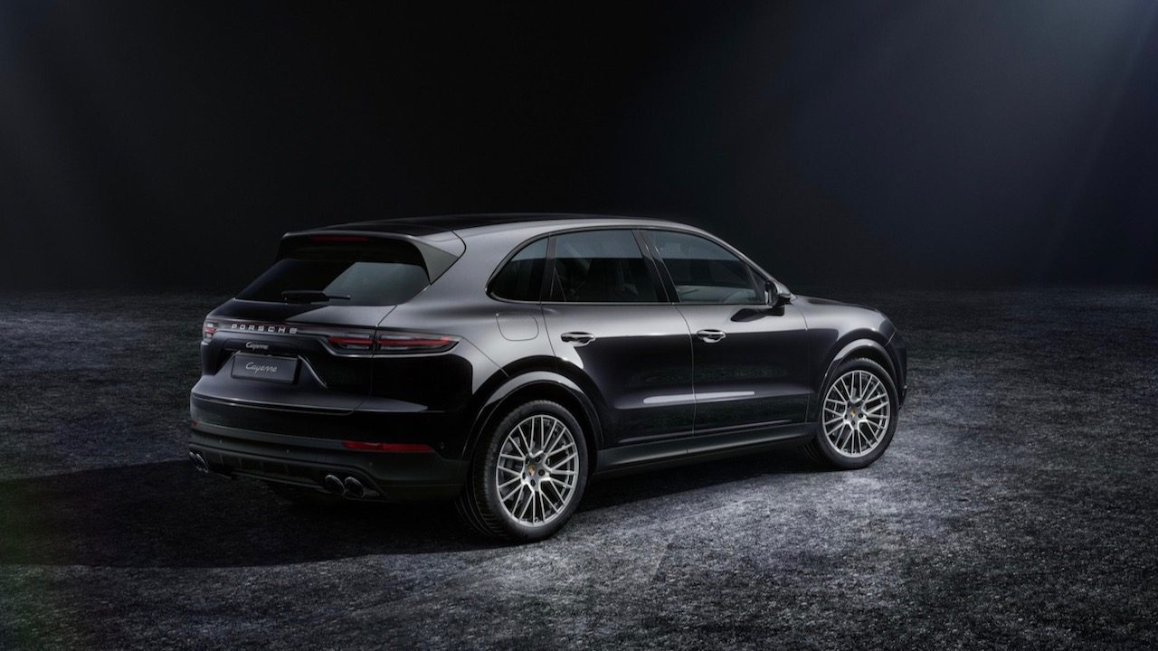 Vista trasera de dos cuartos de la Porsche Cayenne Platinum Edition 2022 en estacionada en un estudio con fondo negro.