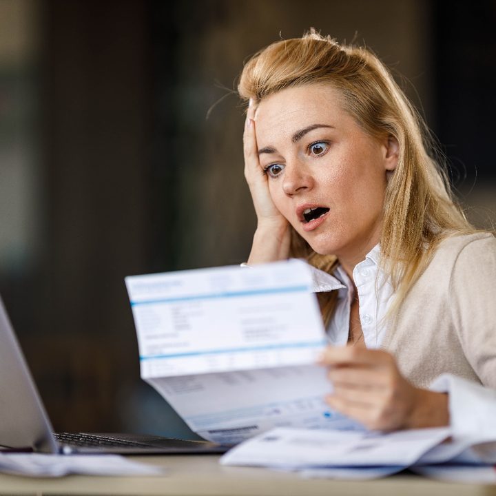 Una mujer con mira cara de sorpresa su cuenta de impuestos.