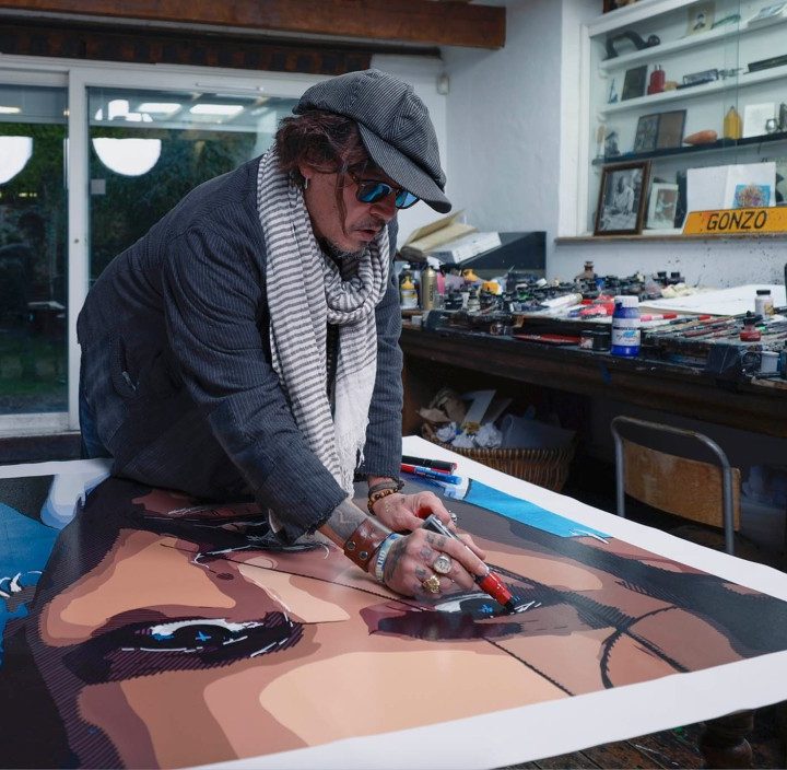 La imagen muestra al actor Johnny Depp pintando un cuadro.