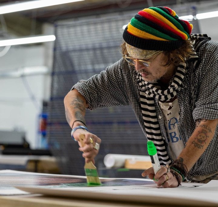 La imagen muestra al actor Johnny Depp pintando un cuadro.