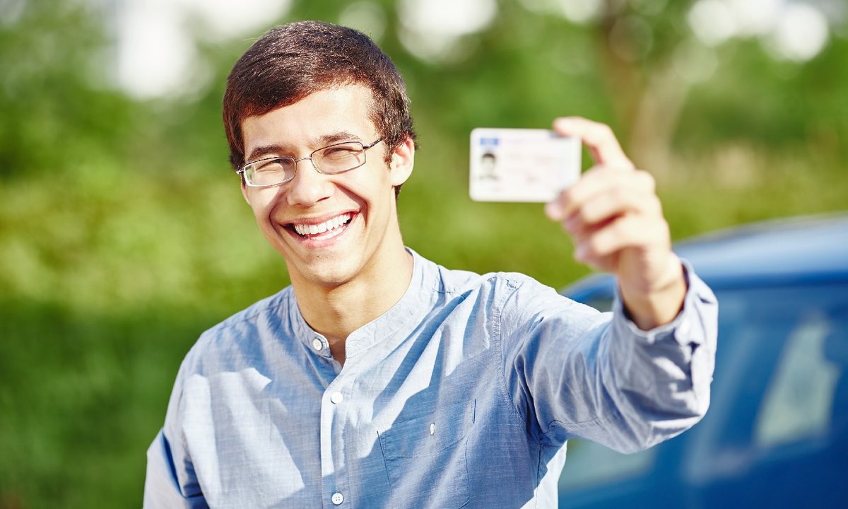 Una persona sonríe mientras muestra su licencia de conducir