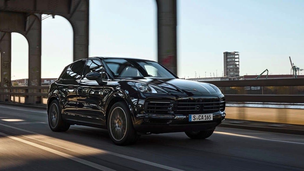 Vista frontal de dos cuartos de la Porsche Cayenne Platinum Edition 2022 en movimiento en un ambiente urbano.