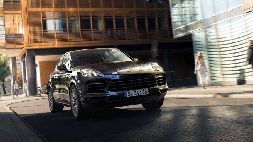 Vista frontal de dos cuartos de la Porsche Cayenne Platinum Edition 2022 en movimiento en un ambiente urbano.