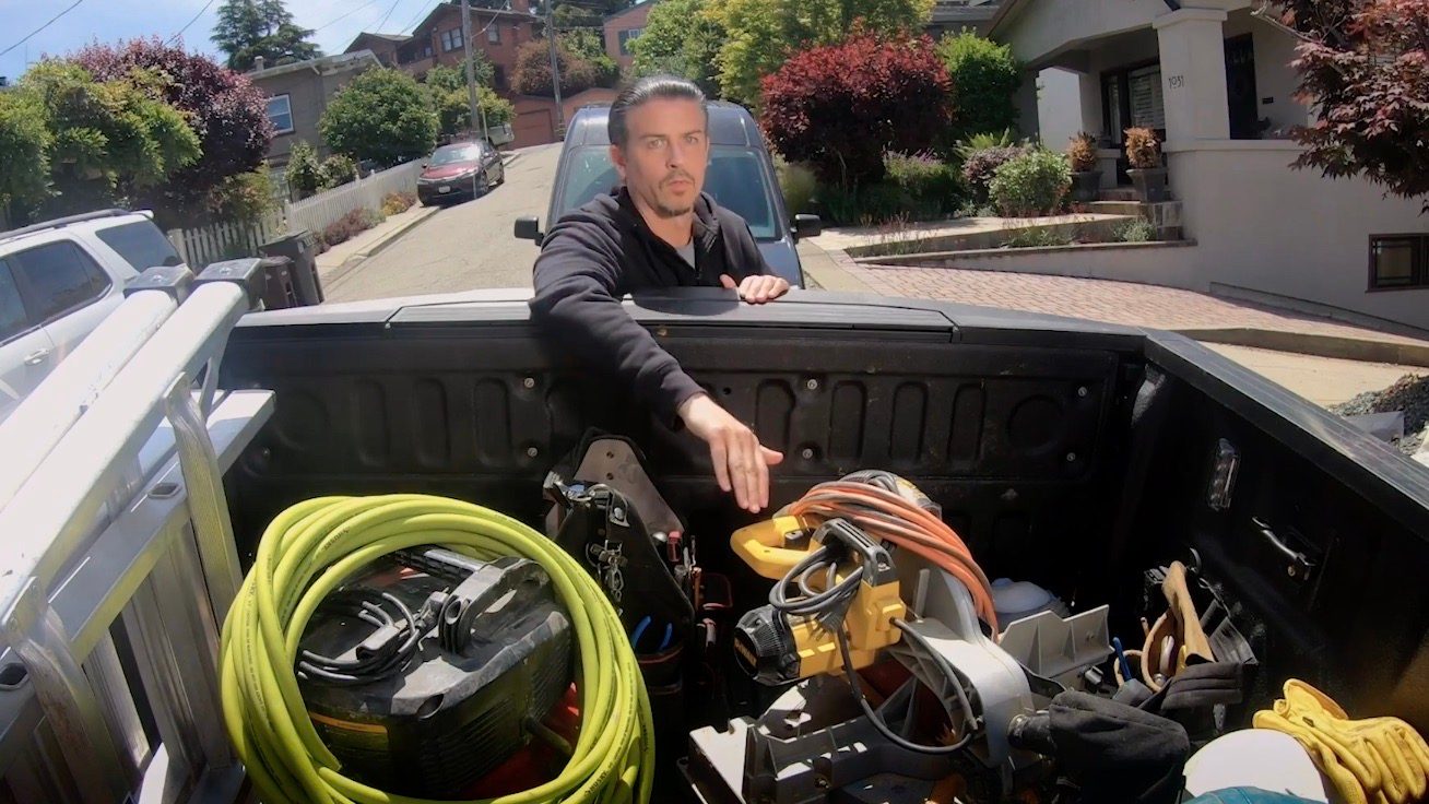 Un ladrón trata de alcanzar con su mano los equipos contenidos en la caja de carga de una pickup.