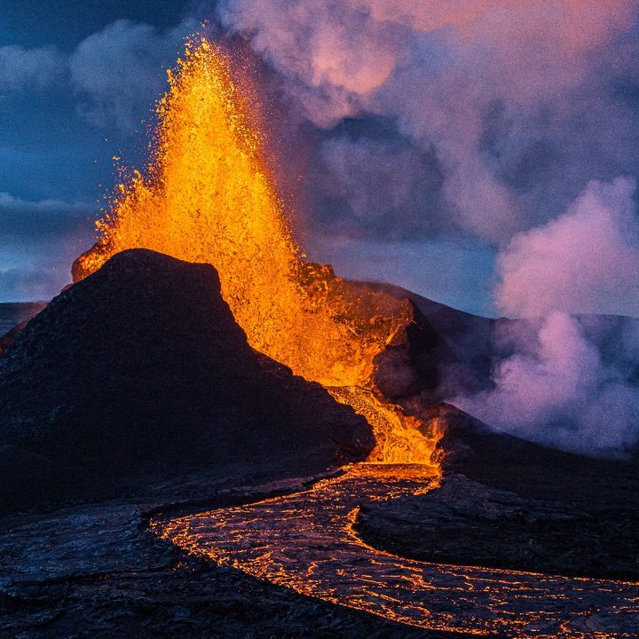 Un volcán hace erupción, expulsando un río de lava, cenizas y dejando una estela de humo que oscurece el lugar.