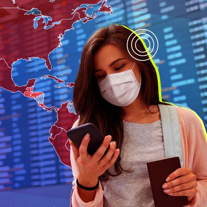 Una mujer en el aeropuerto sosteniendo un celular y un pasaporte.