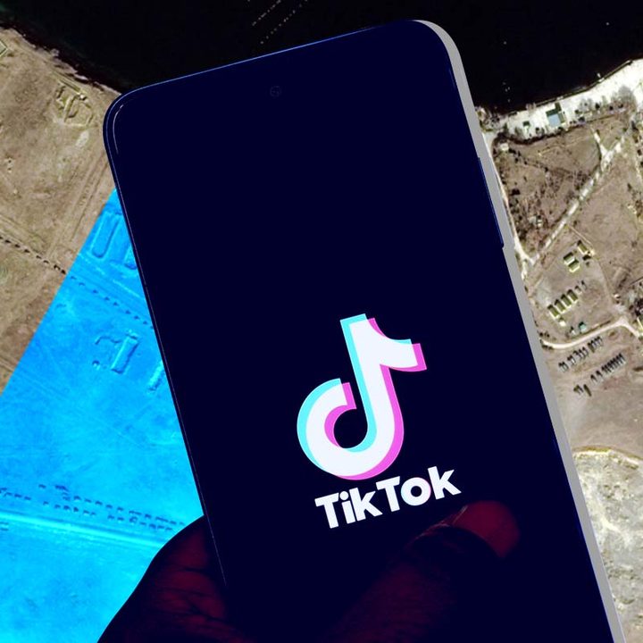 Un celular con el logo de la aplicación TikTok. En el fondo, una vista aérea del área de Novoozerne y el Lago Donuzlav.