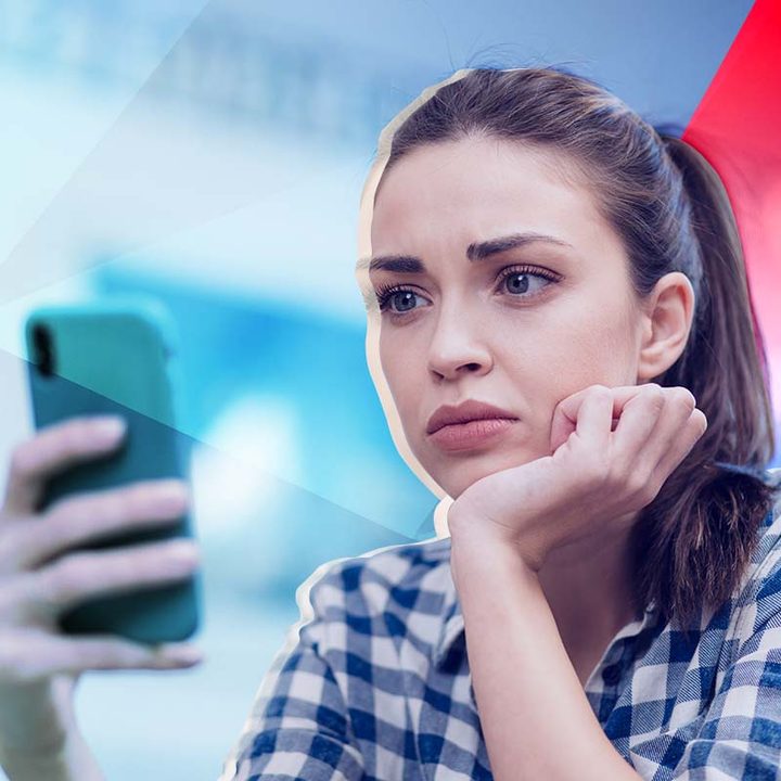 Una mujer con una expresión de angustia mirando su celular.