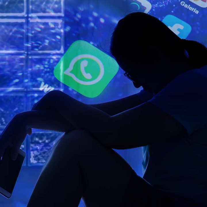 Una persona sentada en el suelo con el celular en la mano, sobre un fondo con el logo de WhatsApp.
