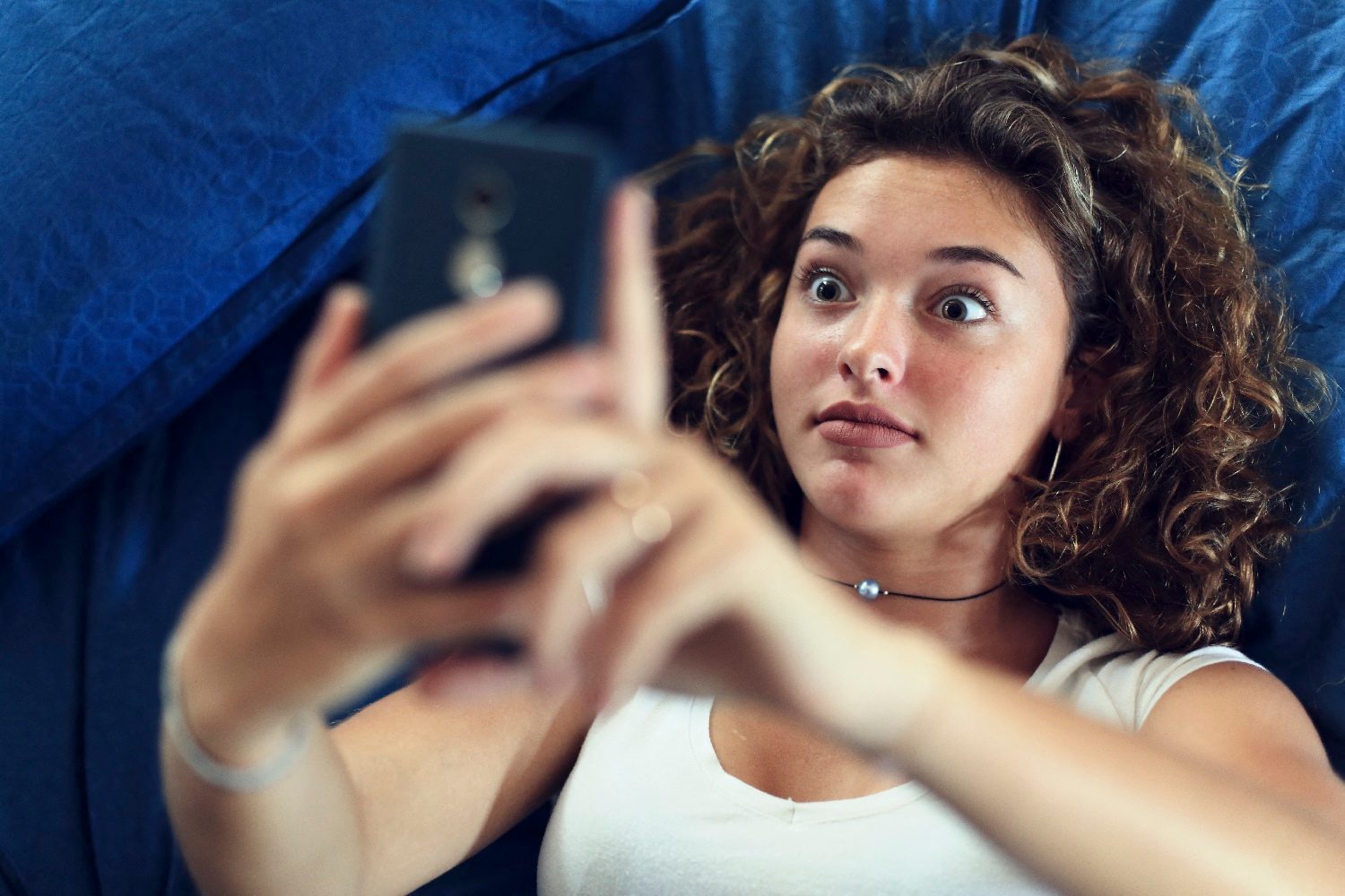 Una adolescente mira su teléfono con cara de sorpresa