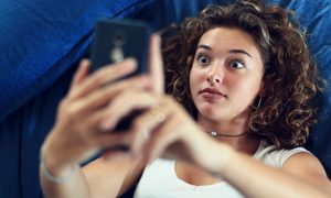 Una adolescente mira su teléfono con cara de sorpresa