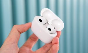 Una mano sostiene unos AirPods 3 en su estuche.
