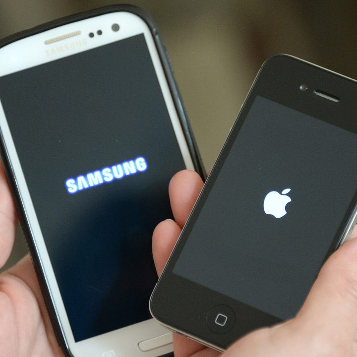 Una persona sostiene un teléfono iPhone 4S y un Galaxy S3