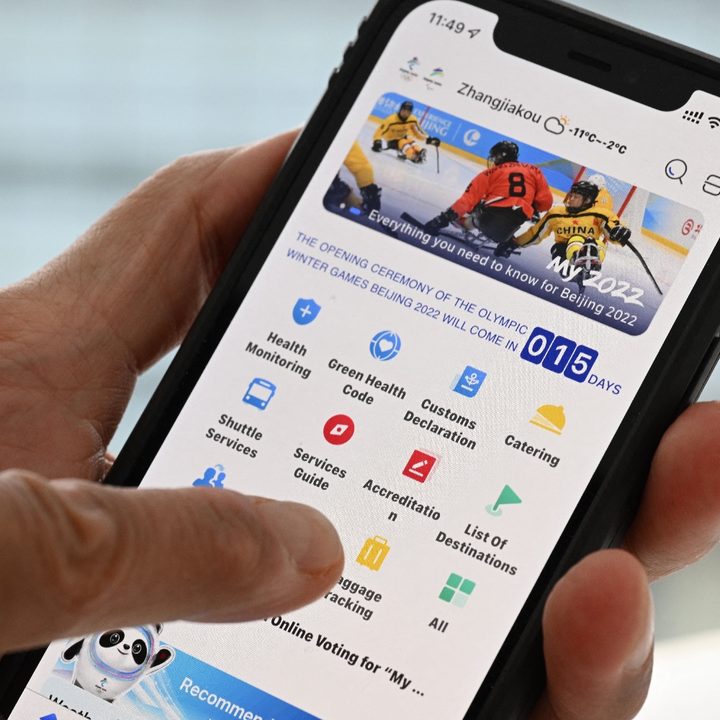 Una persona sostiene un teléfono con una aplicación para seguir los Juegos Olímpicos de Invierno 2022.