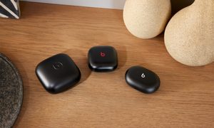 Varios modelos de audífonos Beats en tono negro sobre una superficie que parece ser de madera.