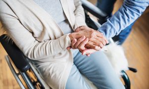 Una paciente en silla de ruedas recibe la ayuda de un enfermero.