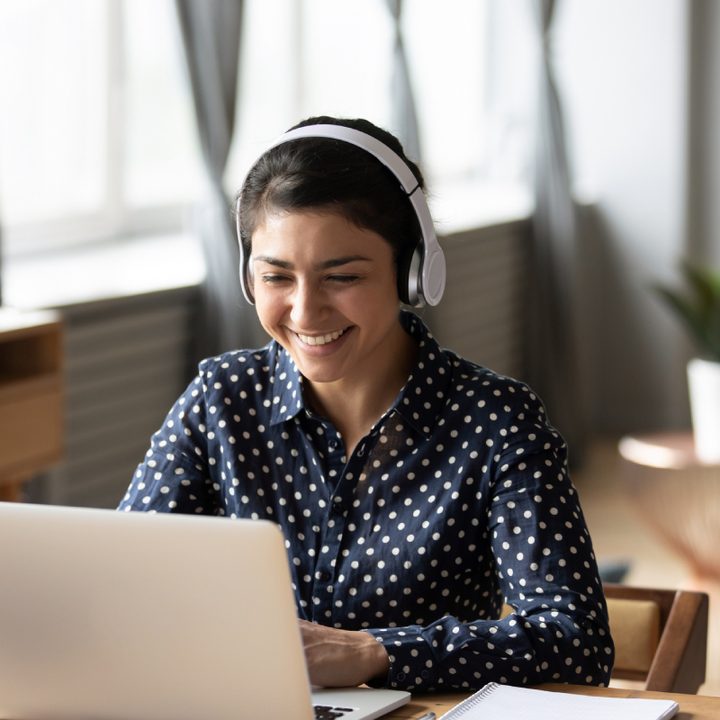Mujer joven frente a una computadora portátil en el interior de una casa.
