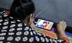 La imagen muestra a una mujer viendo un video de YouTube en su celular.
