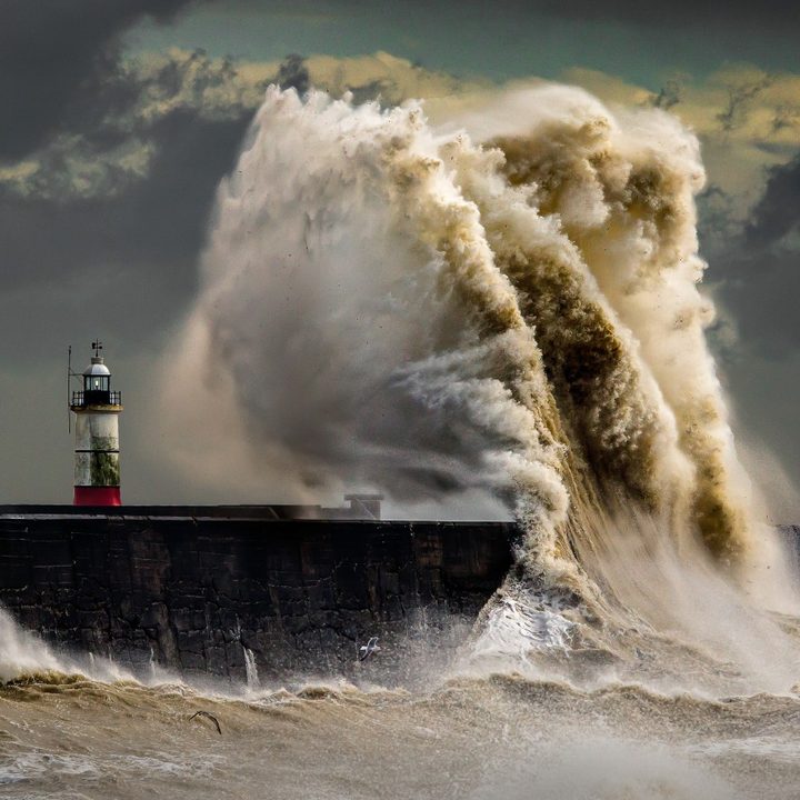 Una violenta olea golpea un faro.