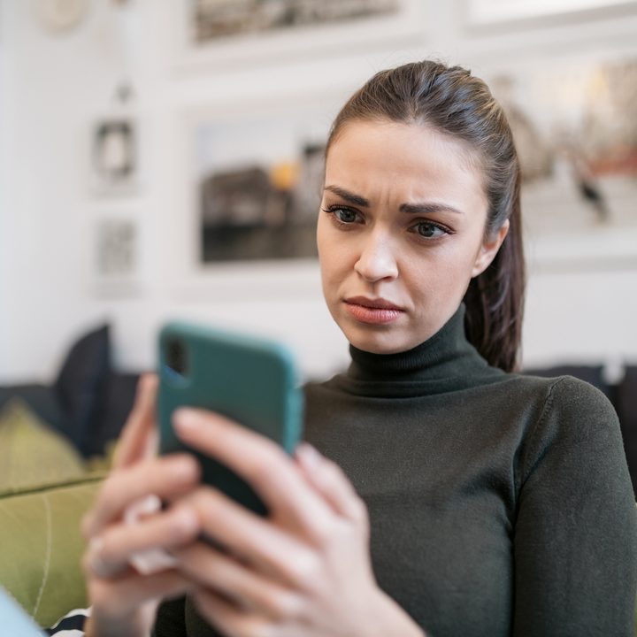 Una mujer observa la pantalla de su celular.