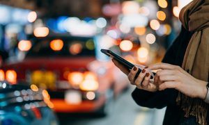 Una mujer revisa su celular a un costado de la calle.