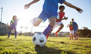 Un grupo de niños juega fútbol en una cancha.