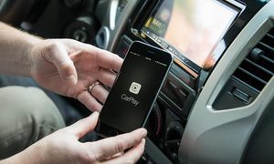 Un hombre dentro de un auto con un iPhone en la mano para configurar Car Play.