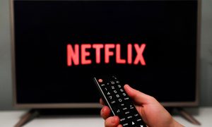Un televisor muestra el logo de Netflix mientras una mano apunta con un control remoto.
