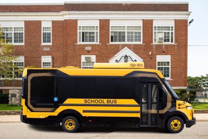 vista lateral del autobús escolar eléctrico Tipo A de BYD frente a una edificación.