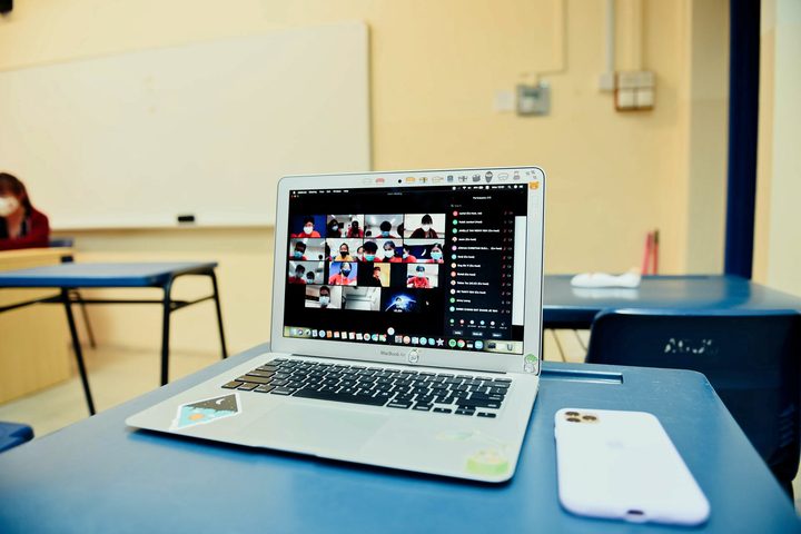 Una videoconferencia de Zoom en la pantalla de una MacBook en un salón de clases.