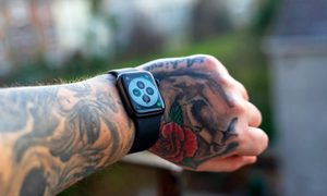Un brazo tatuado con un Apple Watch en la muñeca.