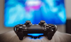 Un control de PlayStation 4; en el fondo fuera de foco se ve un televisor.