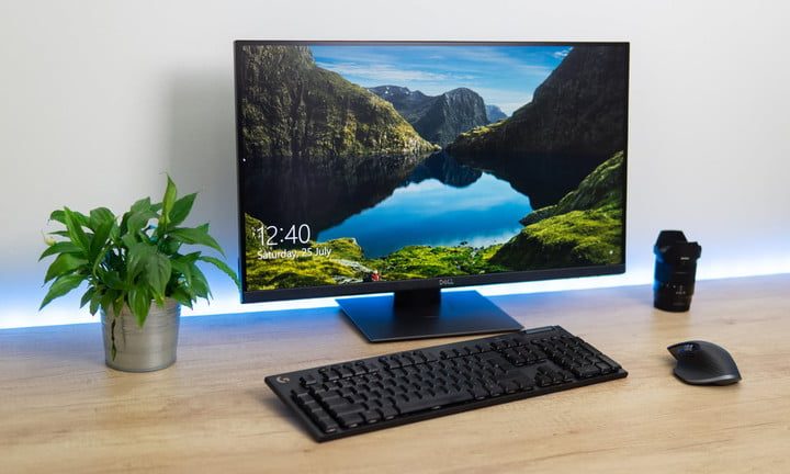 El monitor Dell P2720DC en un escritorio junto a una planta.