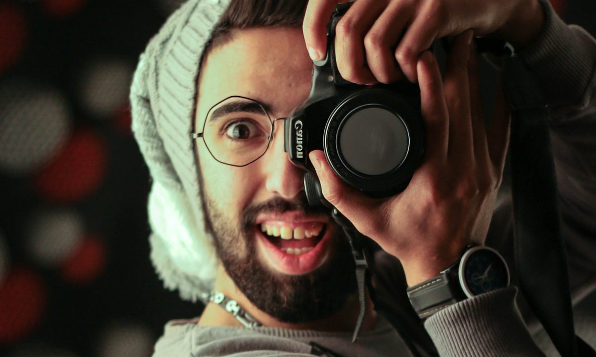 Un hombre apunta a la cámara con una cámara DSLR Canon.