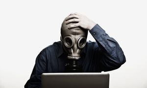 Un hombre usa una máscara de gas mientras está frente a su computadora.