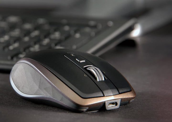 Logitech MX Anywhere 2S junto a un teclado sobre una superficie oscura.