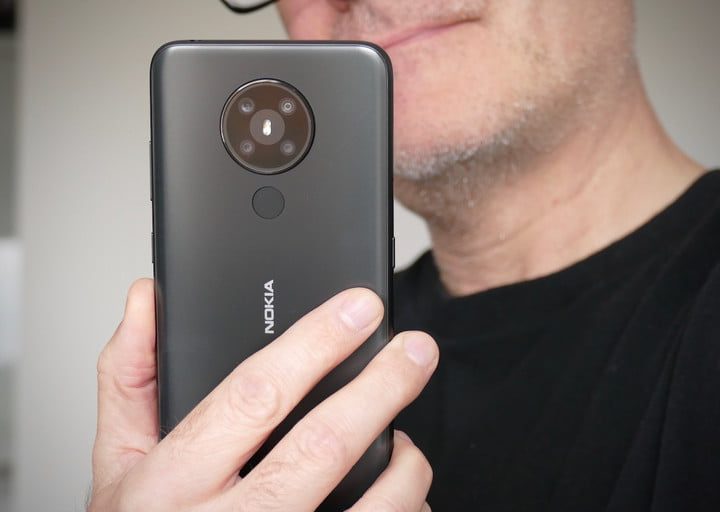 Un hombre mostrando un Nokia 5.3 de la parte posterior.